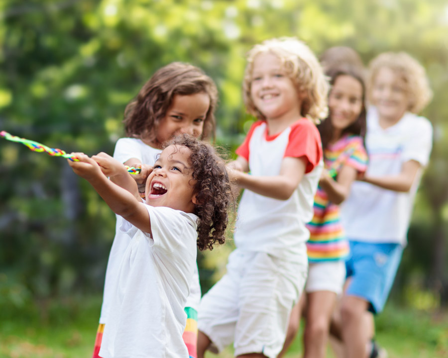 Kids play tug of war. Children pull rope.